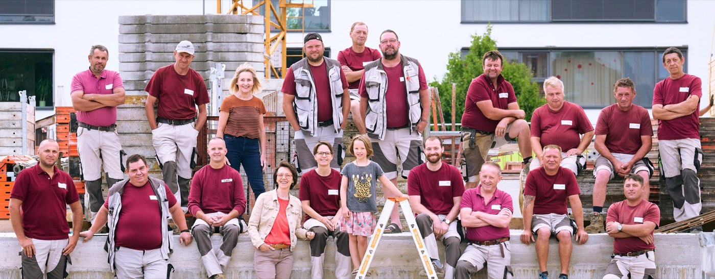 Das Team der Hinner Bauunternehmung vor einem Baustellenfahrzeug